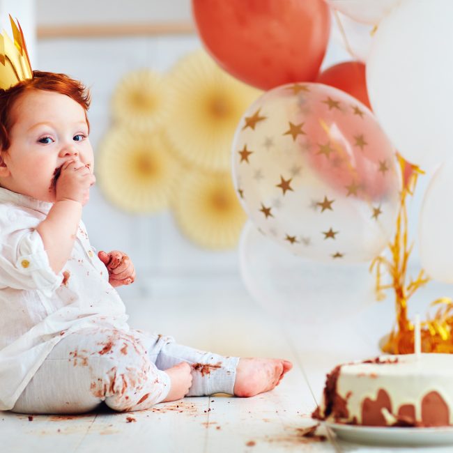 Ein Baby mit Geburtstagskrone und Torte feiert ersten Geburtstag